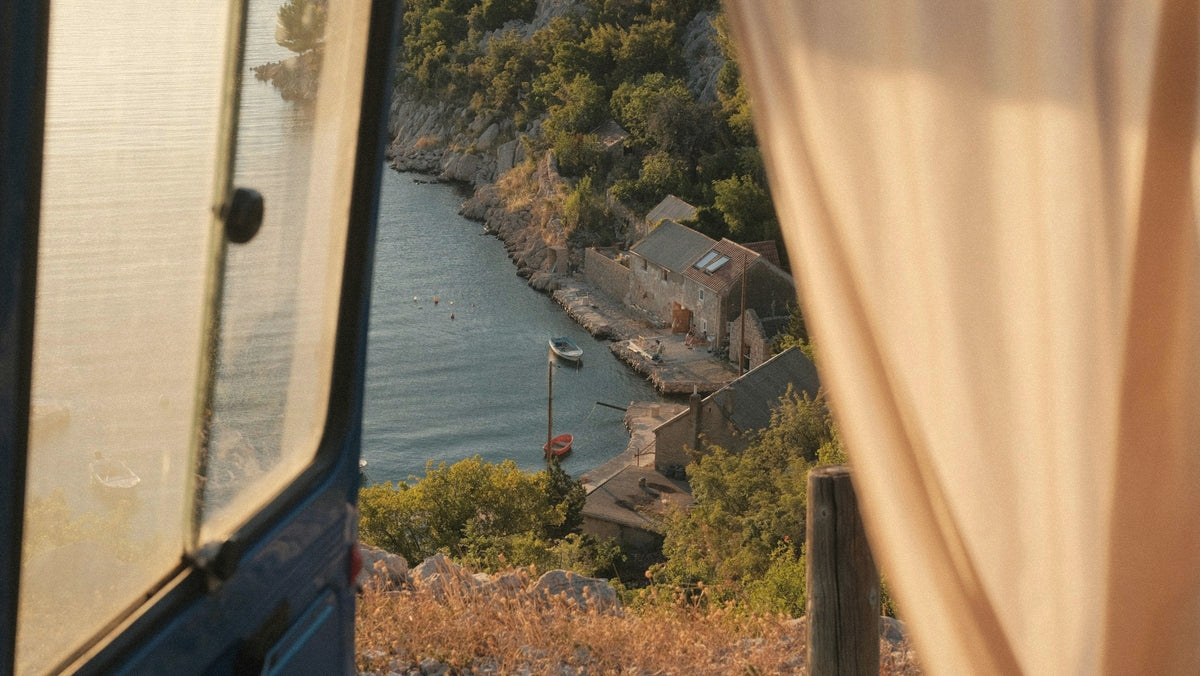 View from a moving window down onto a small stone harbour, a curtain at the edge