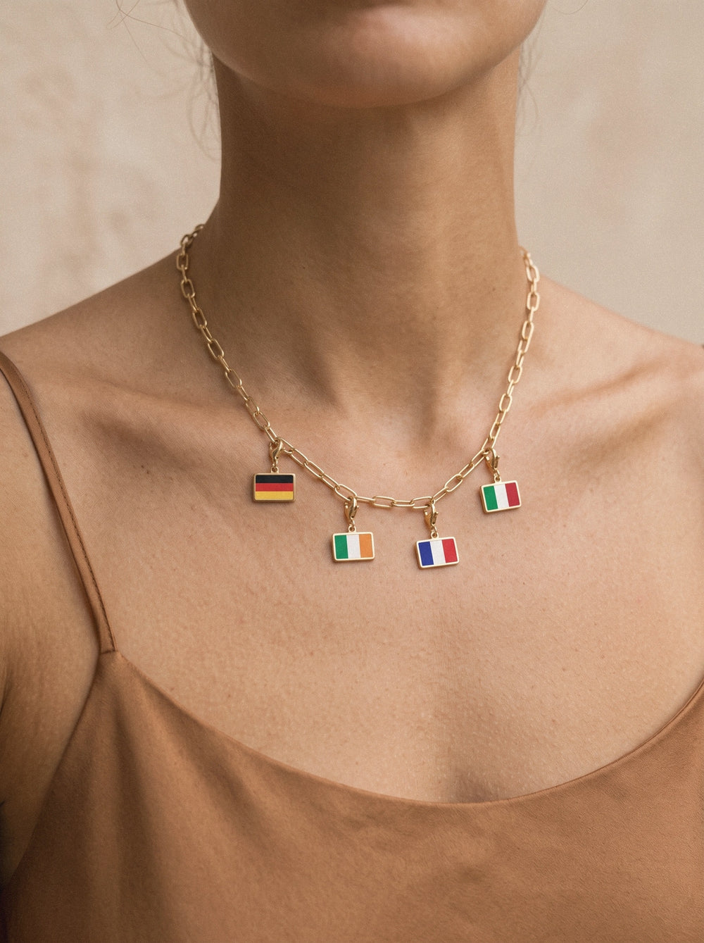 Gold travel charm necklace with four flag charms at the collarbone